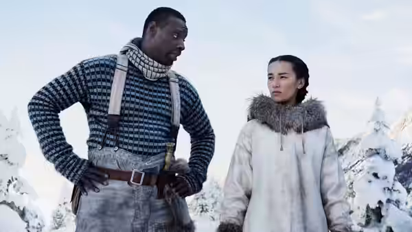Perrault (Omar Sy) stands with Françoise (Cara Gee) in a snowy mountain landscape