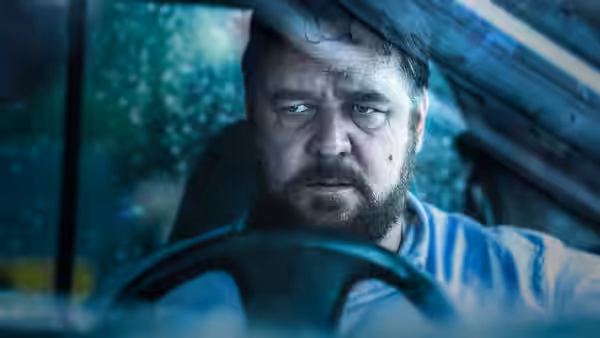Tom Cooper (Russell Crowe) grips the steering wheel inside a rain-soaked car