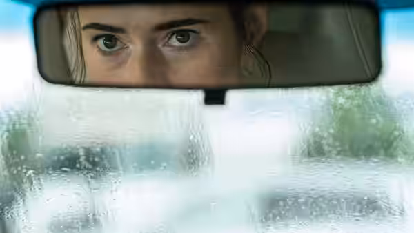 Rachel Flynn (Caren Pistorius) watches the road through her car’s rearview mirror