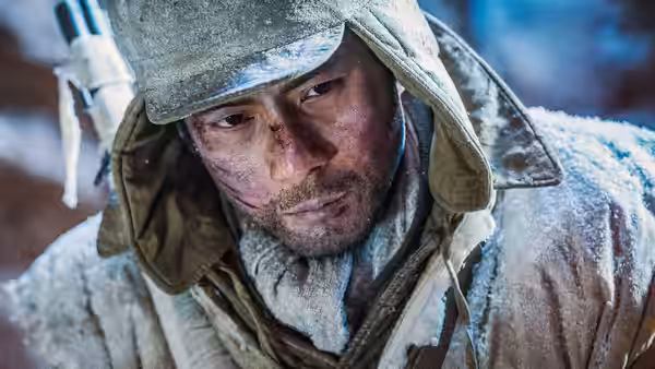 A frost-covered soldier in winter gear looks aside on a snowy battlefield