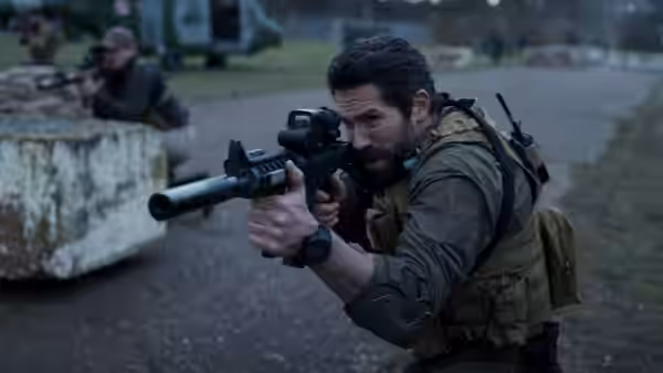 Jake Harris (Scott Adkins) advances with a rifle past concrete barriers