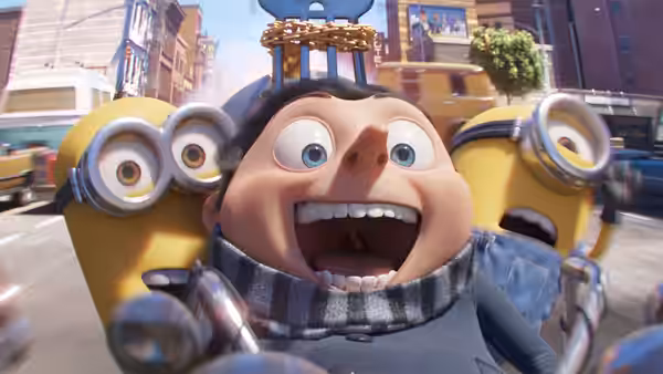 Young Gru (Steve Carell) grins as Minions (Pierre Coffin) crowd around him on a city street