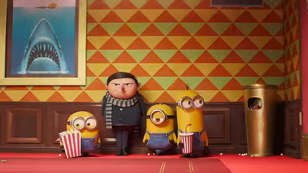 Gru (Steve Carell) and Minions (Pierre Coffin) stand with popcorn in a theater hallway
