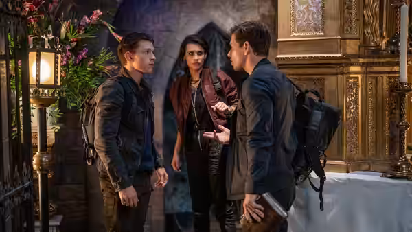 Nathan Drake (Tom Holland), Chloe Frazer (Sophia Ali), and Sully (Mark Wahlberg) talk inside an ornate building