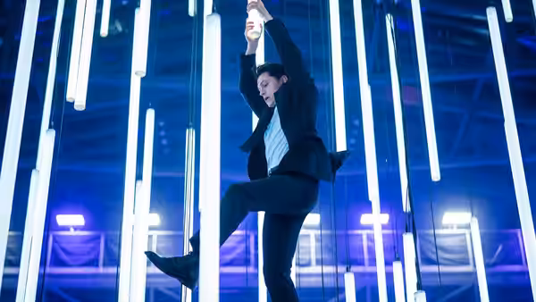 Jo Braddock (Tati Gabrielle) climbs through a room filled with glowing vertical light tubes