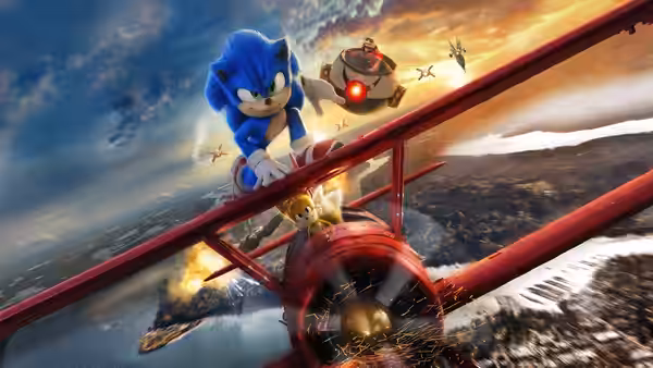 Sonic rides atop a red biplane as Tails pilots it through the sky, pursued by a robot