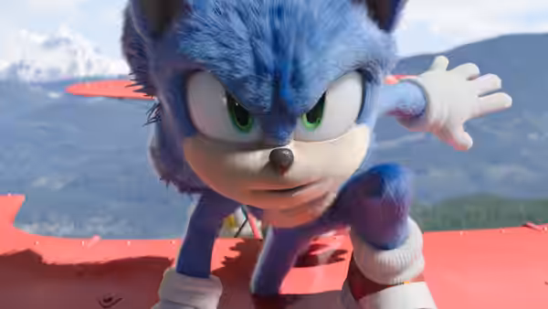 Sonic crouches on a red biplane wing with mountains in the distance