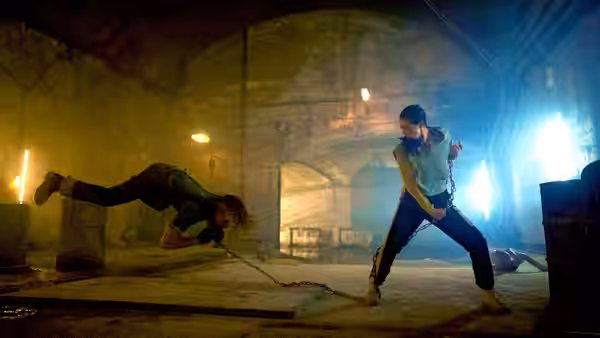 Mike Fallon (Scott Adkins) swings a chained opponent across a cellar