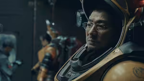 Tu Hengyu (Andy Lau) in an orange spacesuit, looking to the side among crew members