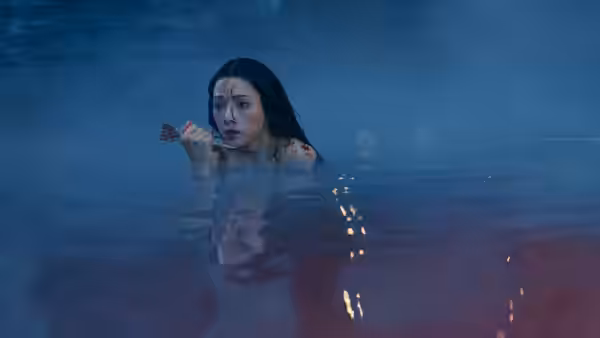 A woman with bloodied shoulders clings to a small branch while submerged in water