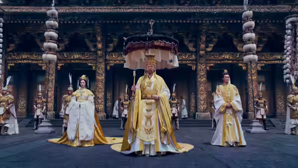 King Zhou (Fei Xiang) stands beneath a ceremonial canopy between two women in the palace courtyard