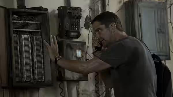 Brodie Torrance (Gerard Butler) works a wall-mounted communications panel inside a building