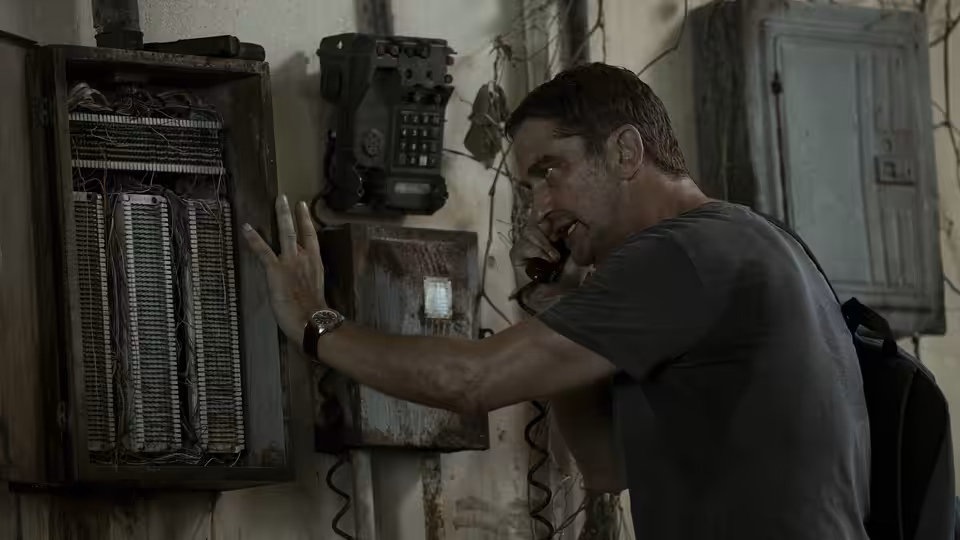 Brodie Torrance (Gerard Butler) works a wall-mounted communications panel inside a building