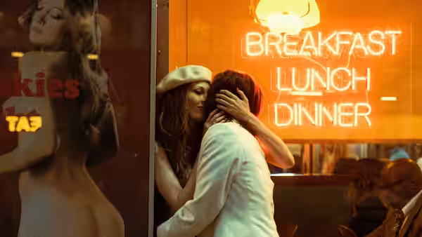 Eddie Limonov (Ben Whishaw) embraces a woman beneath a diner’s neon sign
