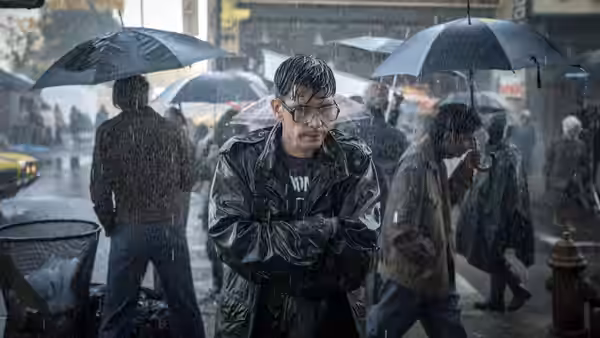 Eddie Limonov (Ben Whishaw) stands with folded arms in a rain-soaked city street