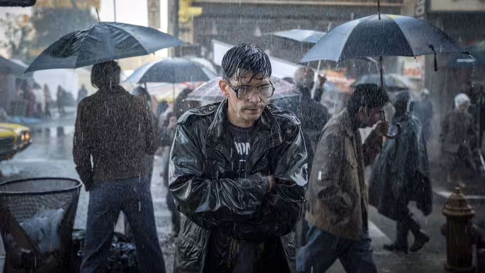 Eddie Limonov (Ben Whishaw) stands with folded arms in a rain-soaked city street