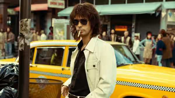 Eddie Limonov (Ben Whishaw) stands beside a yellow taxi on a busy city street