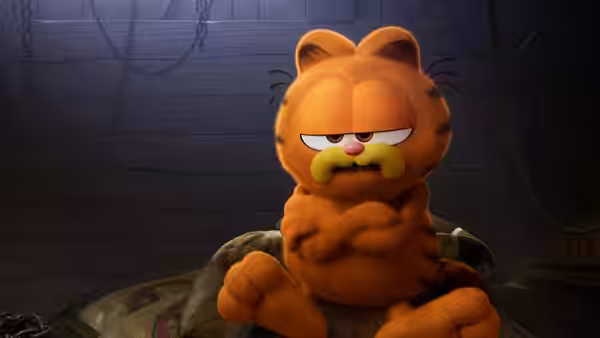 Garfield sits cross-legged with folded arms in a dim wooden room