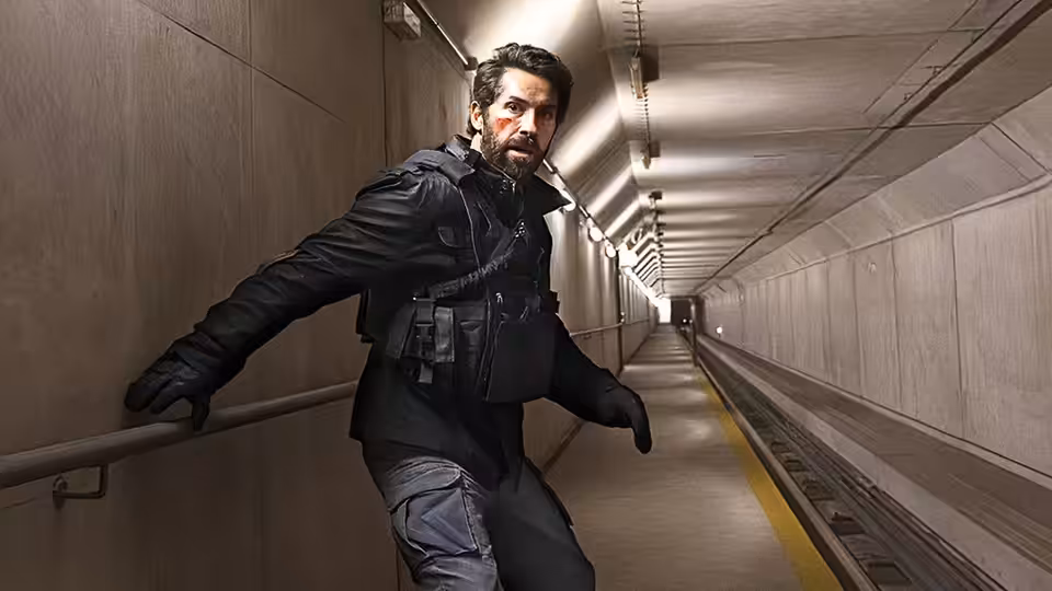 Jake Harris (Scott Adkins) braces against a handrail in a long, narrow corridor