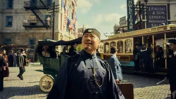 Fei Yanggu (Yue Yunpeng) stands in a busy street beside a horse-drawn carriage