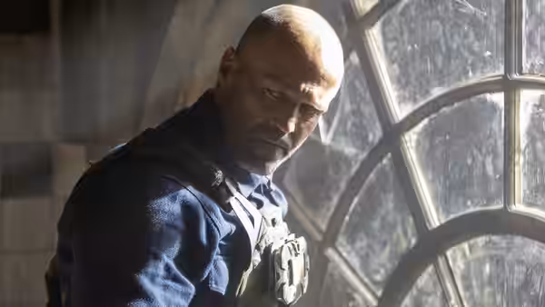 Levon Cade (Jason Statham) stands beside an arched window wearing tactical gear