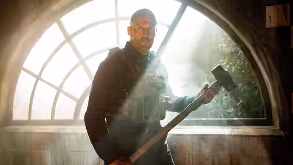Levon Cade (Jason Statham) holds an axe before an arched window