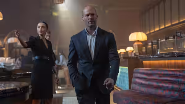 Levon Cade (Jason Statham) walks through a restaurant as a server gestures behind him