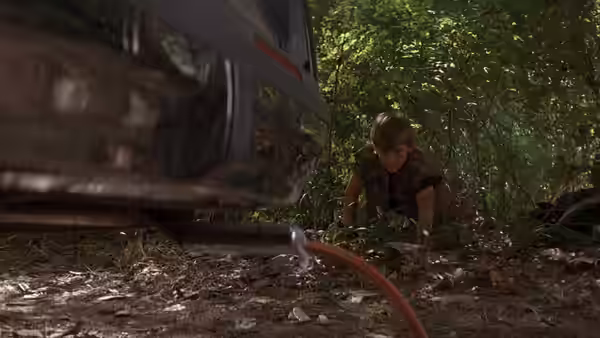 Mark Sway crouches beside a car in the woods, connecting a hose to its exhaust