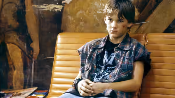 Mark Sway sits alone in a chair inside a rough wooden cabin