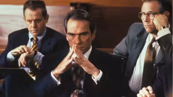 Roy Foltrigg sits with two suited men during a meeting