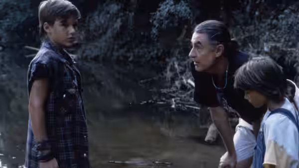 Mark Sway faces a man and a boy beside a wooded creek