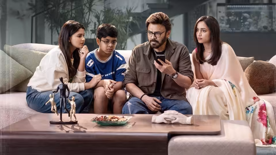 Chittibabu (Venkatesh) checks his phone while seated with a boy and two women on a sofa