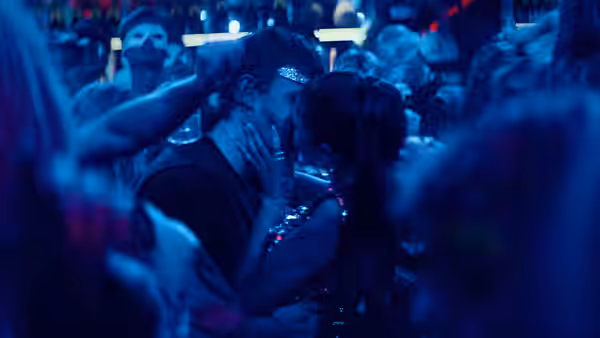 A couple kiss amid a blue-lit nightclub crowd