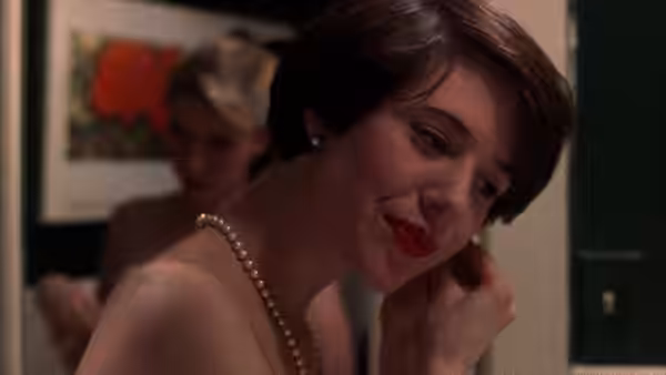 Audrey Rouget (Carolyn Farina) with pearl necklace touches her neck