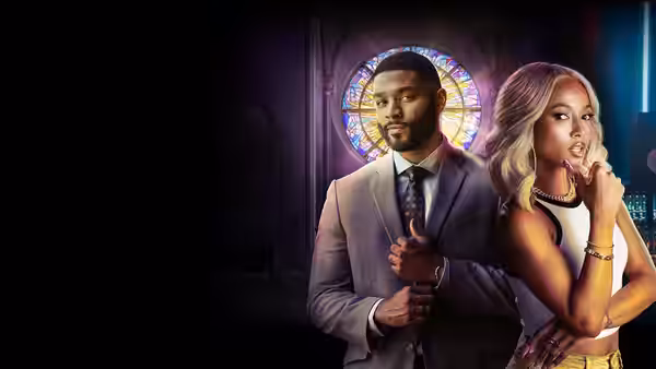 A suited man and blonde woman pose before a stained-glass church window