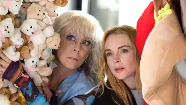 Jamie Lee Curtis and Lindsay Lohan peek from behind piles of stuffed toys