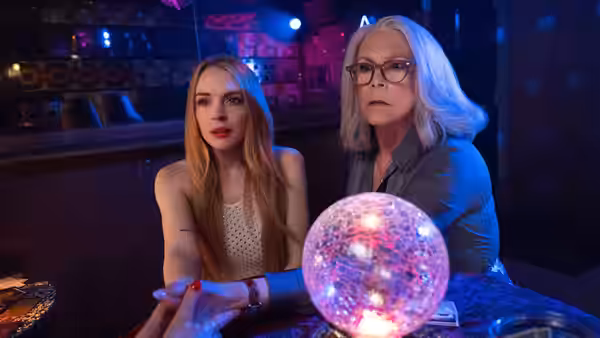 Lindsay Lohan as Anna and Jamie Lee Curtis as Tess examine a glowing orb in a bar