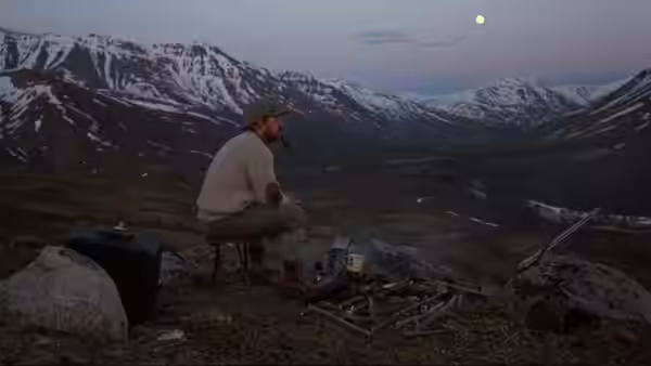 Tyler (Charles Martin Smith) sits beside a campfire, watching the moon rise over the mountains