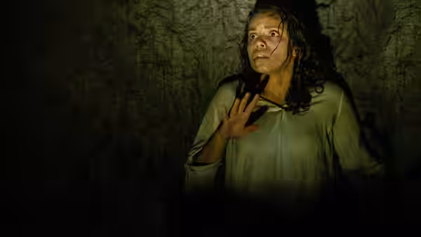 Tess (Georgina Campbell) presses against a stone wall looking terrified