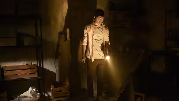 AJ (Justin Long) holds a flashlight in a dim cluttered basement