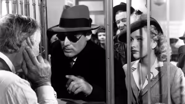 Jonathan Brewster (Raymond Massey) and Elaine Brewster (Priscilla Lane) peer through bars at a man
