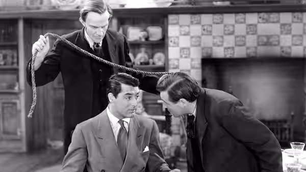 Mortimer Brewster (Cary Grant) sits as a man holds rope above him and another leans close