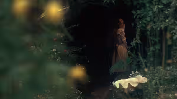 Woman in long dress stands at the entrance to a dark overgrown path