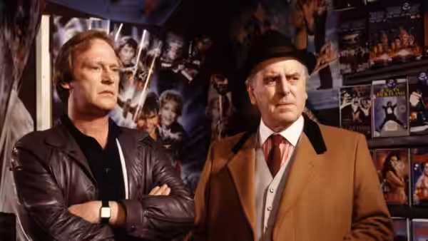 Terry McCann (Dennis Waterman) and Arthur Daley (George Cole) stand among posters in a shop