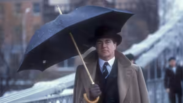Guy Burgess (Alan Bates) carrying an umbrella along a snowy city street