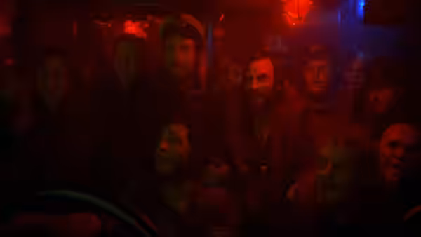 Submarine crew members crowd together beneath red and blue lights