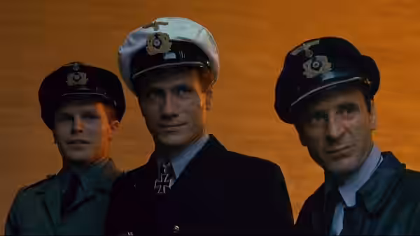 Three naval officers in caps stand together against an orange sky