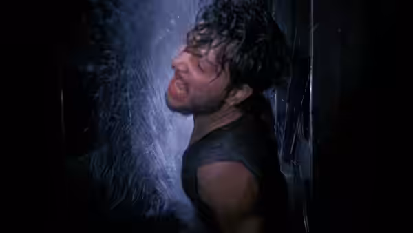 A sailor grimaces as water sprays over him in a narrow passage