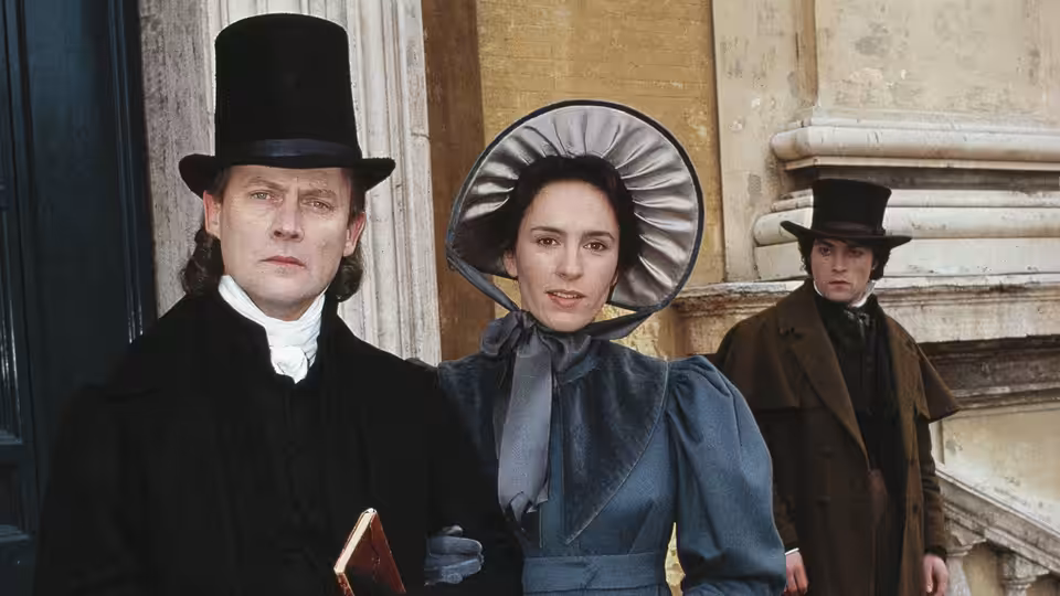 Dorothea Brooke (Juliet Aubrey) stands between two men outside a stone building