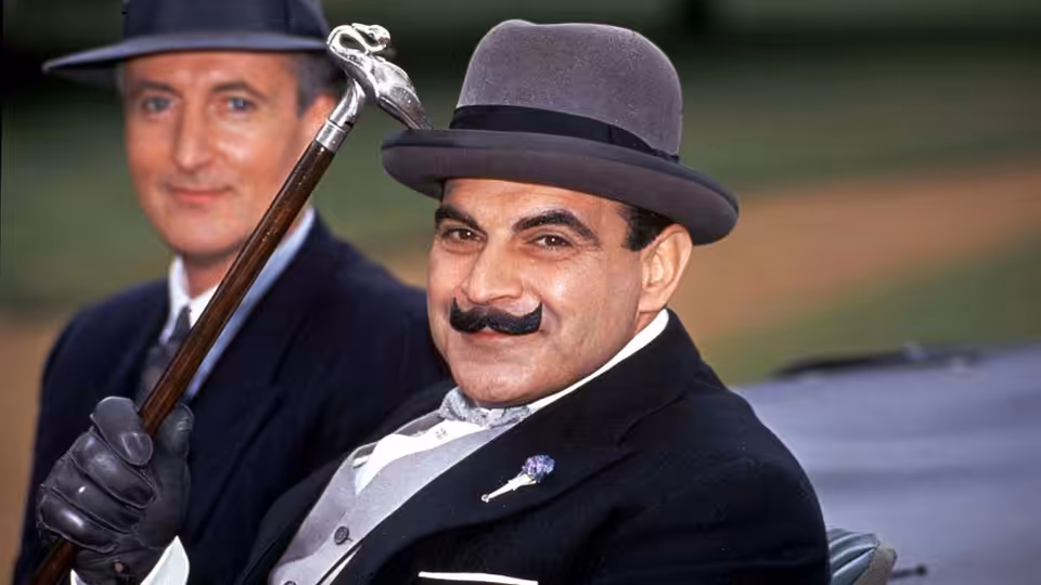 Hercule Poirot (David Suchet) holds his cane beside Captain Hastings (Hugh Fraser) outdoors